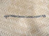a silver chain that is laying on a wooden floor