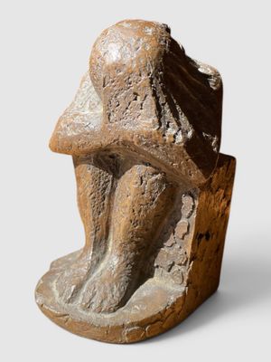 une photo représentant une sculpture d'un homme assis sur un rocher