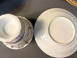 two cups and saucers sitting on a table next to each other