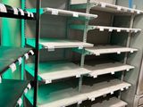 many empty shelves in a store with green lights