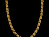 a close up of a gold necklace on a black background