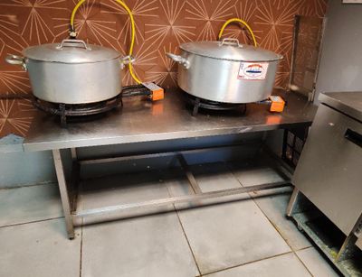 des casseroles et des poêles posées sur une table dans une cuisine avec du papier peint