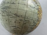 a globe on a stand with a pear on top of it