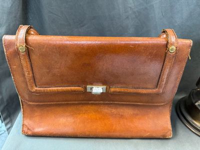 a brown leather purse sitting on top of a table next to a lamp