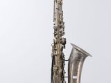 an old silver saxophone on a stand against a white background