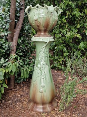 a green vase that is sitting in the middle of a garden