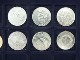 an assortment of silver coins in a display case on a black surface