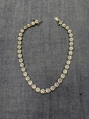 un gros plan d'un collier posé sur un tissu gris