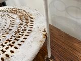 une chaise blanche dont l'assise est rouillée, posée près d'une table en bois