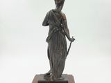 an antique bronze statue of a woman holding a sword on a marble base