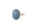 un gros plan d'une bague posée sur une surface blanche, ornée d'une pierre bleue