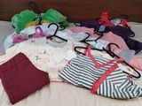 a lot of clothes on a bed with a wooden headboard