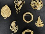 a close up of a bunch of gold brooches on a black surface