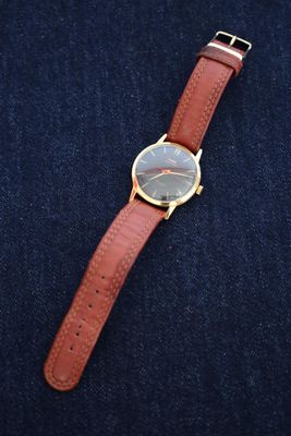 a close up of a watch sitting on top of a pair of jeans