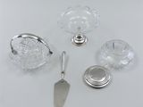 several pieces of silver and glass are arranged on a white surface
