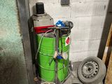 a bucket of red liquid next to a green barrel of water