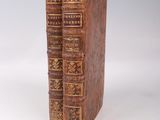 two old books sitting on top of each other on a white surface