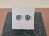 une paire de boucles d'oreilles à clous en pierre verte posée sur une boîte