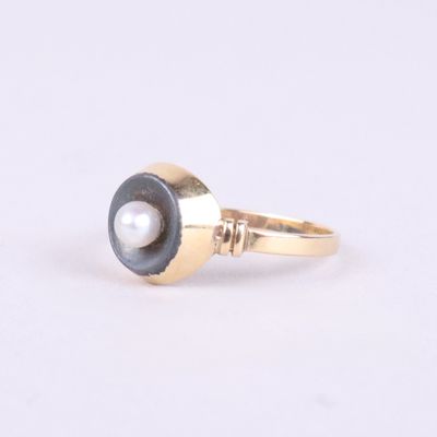 gros plan d'une bague en or avec une perle au centre