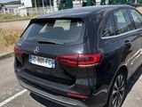 the rear end of a black car parked in a parking lot
