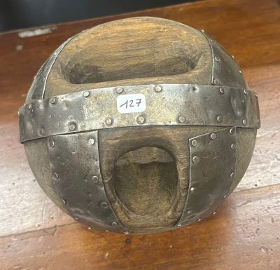 une boule métallique percée d'un trou, posée sur une table en bois