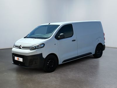 La camionnette blanche est garée dans une grande pièce aux murs blancs.