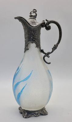 une image représentant un vase en verre muni d'une poignée en argent, sur fond blanc