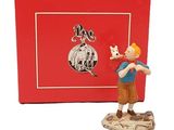La figurine se trouve dans une boîte rouge sur laquelle est représenté un garçon tenant un chien dans ses bras.