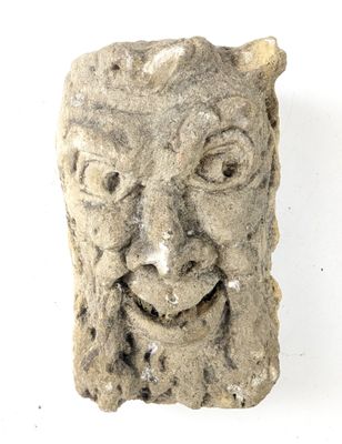 une sculpture en pierre représentant un visage sur une surface blanche