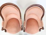pair of pink velvet slippers with wooden feet on a white surface