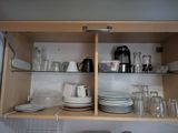many plates and glasses on the shelves in the kitchen