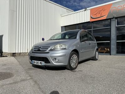 La petite voiture est garée devant un grand immeuble.