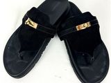 une paire de pantoufles noires ornées de boucles dorées sur un fond blanc