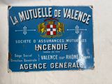 panneau accroché au mur d'un immeuble et orné d'un blason
