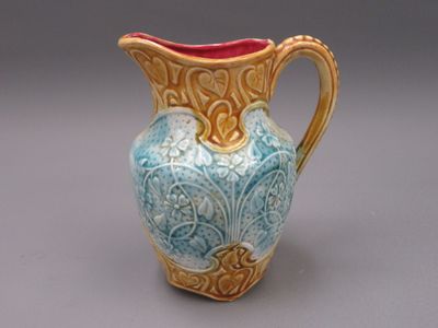 un vase bleu et jaune avec une anse rouge sur un fond gris