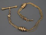 un collier en or et une paire de boucles d'oreilles posés sur une surface grise