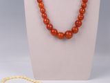 an orange and white beaded necklace on a mannequin