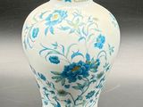 a white vase with blue flowers on it on a table