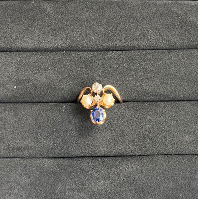 un gros plan d'une bague en or sertie d'une pierre bleue et blanche