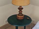 une petite table sur laquelle est posée une lampe, à côté d'un lit