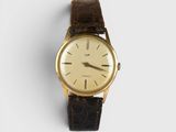 a close up of a watch on a white surface with a brown strap