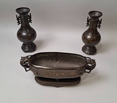 trois vases en métal posés les uns à côté des autres sur une table