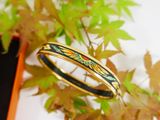 an image of a ring with a dragon on it sitting next to a plant