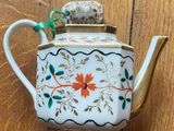 an old teapot on a wooden table with a green handle
