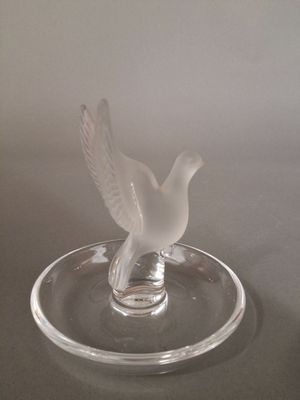 a glass bird sitting on top of a glass plate