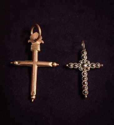 two silver and gold cross pendants on a black background