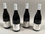 quatre bouteilles de vin sont alignées sur une surface blanche