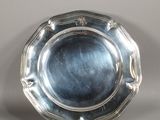 un plat ancien en argent posé sur un socle, sur une surface grise