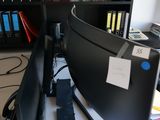 a desk with a computer monitor and bookshelf in the background