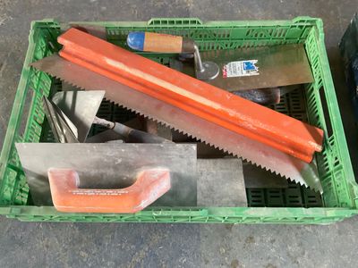 une caisse verte contenant des outils, posée par terre